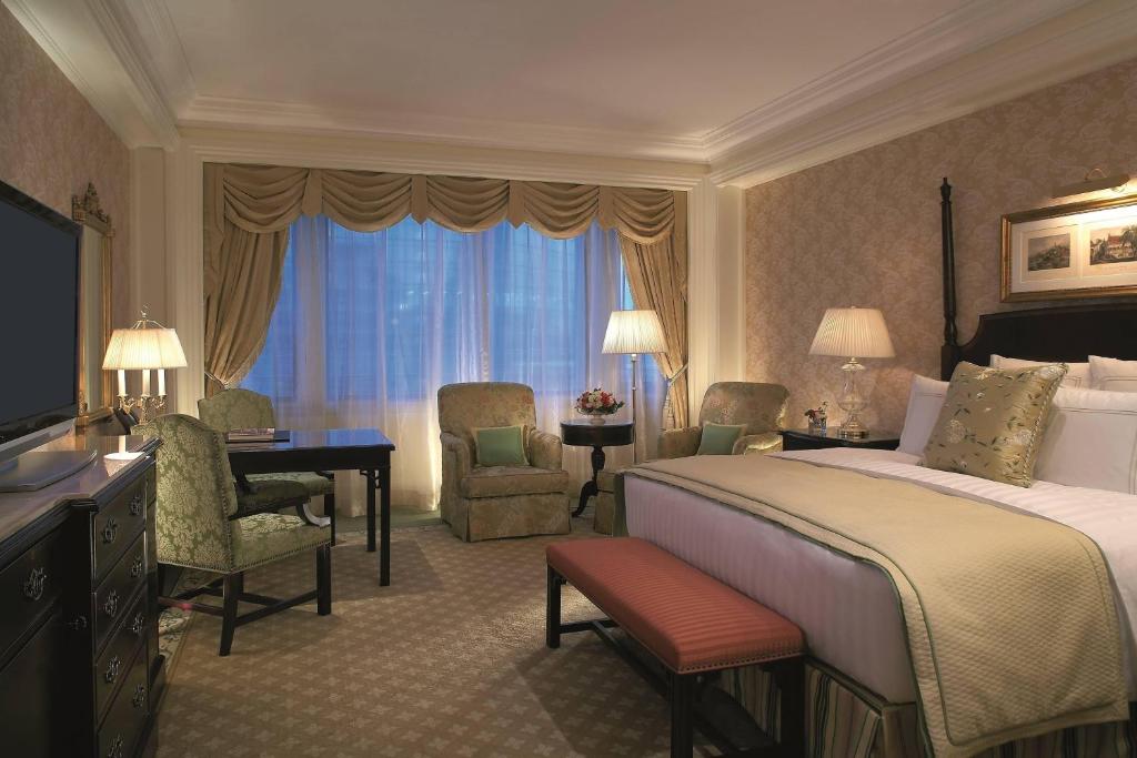 um quarto de hotel com uma cama, uma secretária e cadeiras em The Ritz-Carlton Beijing em Pequim