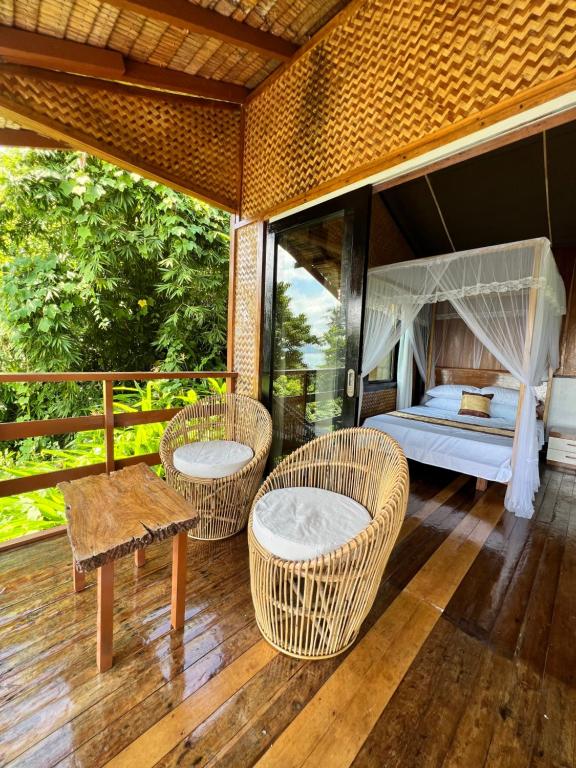 a room with a bed and chairs on a deck at Ursula Beach Resort in El Nido