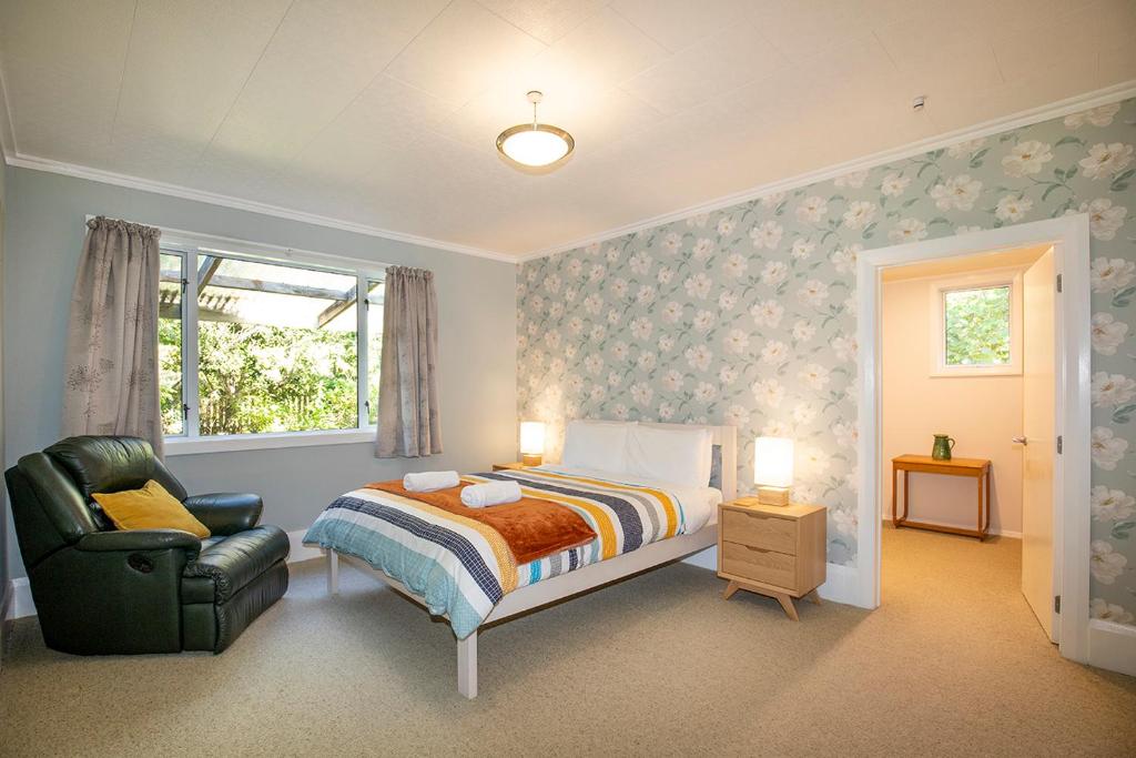 普納凱基的住宿－Cliffscapes，卧室配有床、椅子和窗户。
