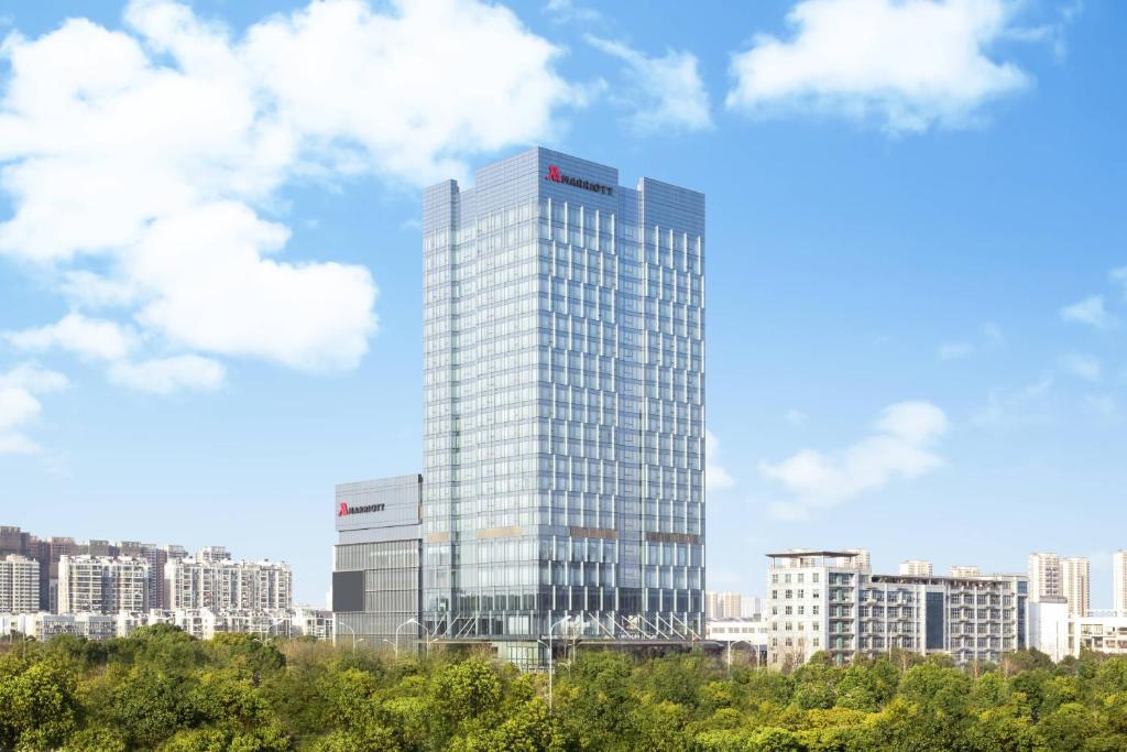 a tall glass building in front of a city at Marriott Nanjing South Hotel in Jiangning