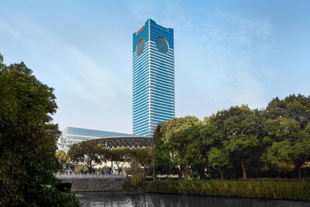 wysoki niebieski budynek z rzeką przed nim w obiekcie Suzhou Marriott Hotel w mieście Suzhou