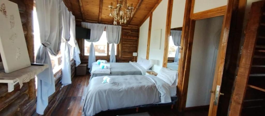 1 dormitorio con 2 camas y lámpara de araña en INCA ROCA Cabañas de Montaña en Uspallata