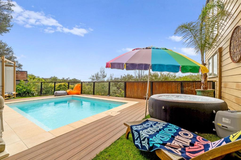 a swimming pool with an umbrella and a chair at Ourania Luxury Villa with unforgettable sea views in Rye