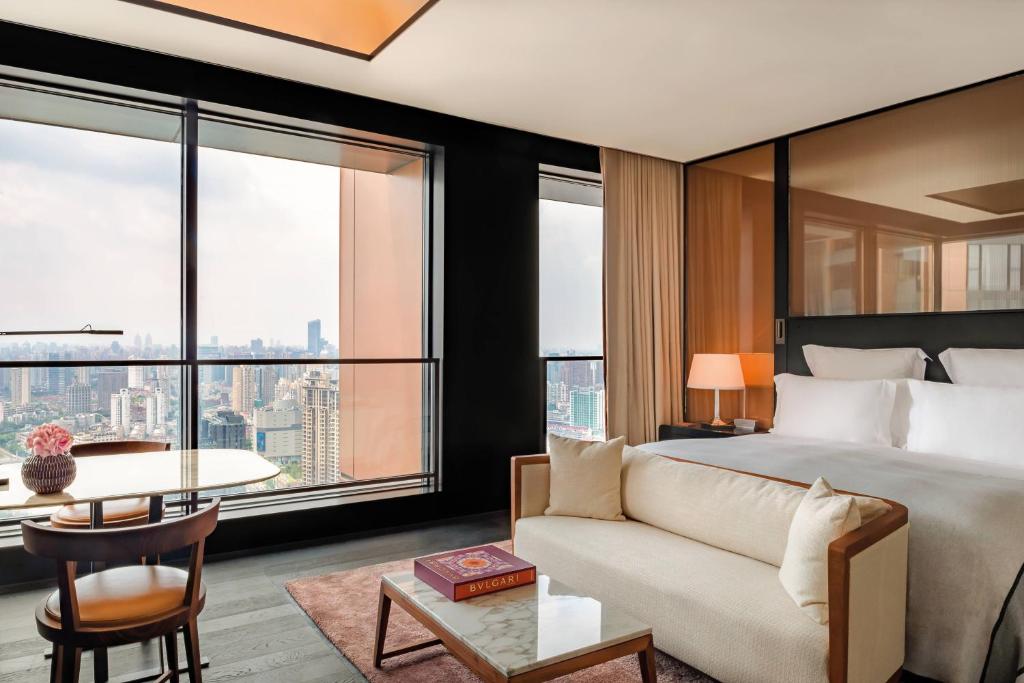 Bulgari Hotel Shanghai في شانغهاي: غرفة نوم بسرير واريكة وطاولة