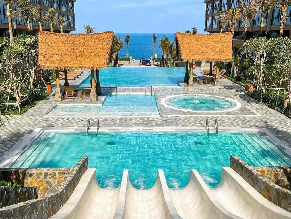 a swimming pool with blue water in front of a building at APEC MANDALA CONDOTEL - Mui Ne in Mui Ne