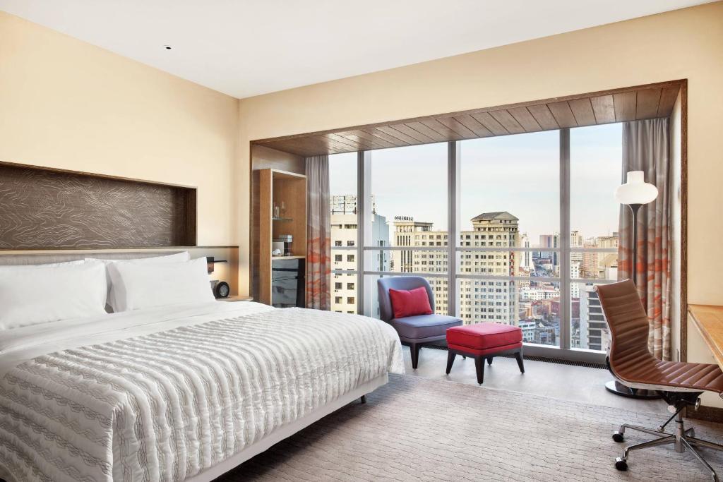 a hotel room with a bed and a large window at Le Meridien Shenyang Heping in Shenyang