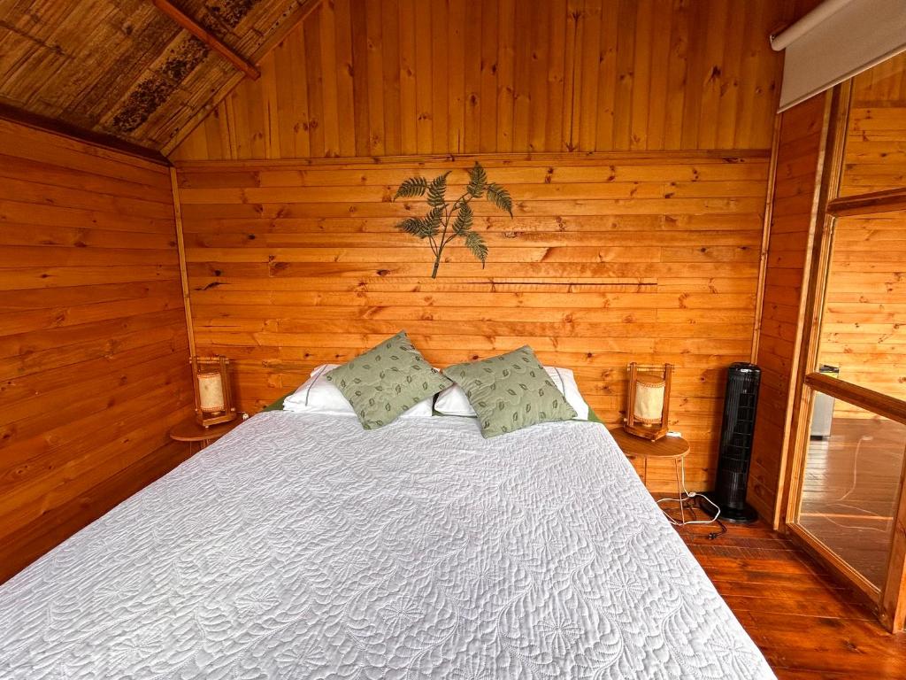 um quarto com uma cama branca e paredes de madeira em Tropical House em La Vega