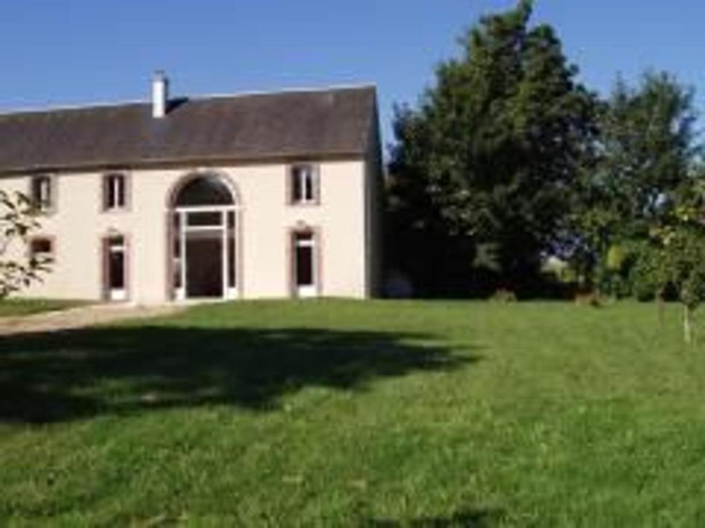 una grande casa bianca con un grande cortile erboso di Gîte Ouzouer-sur-Trézée, 4 pièces, 8 personnes - FR-1-590-383 a Ouzouer-sur-Trézée