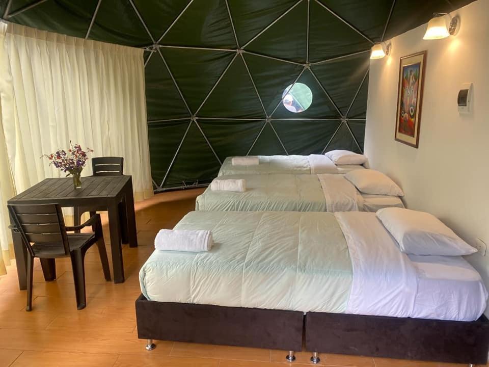 a bedroom with a large bed and a table with a table sidx sidx at Sky Lodge Domes Loreta Playa Sahuayaco in Sahuayacu