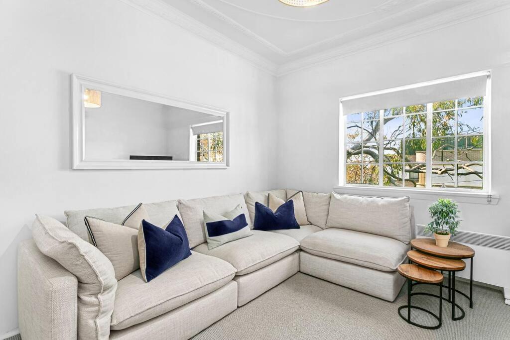 a white living room with a couch and a window at Harriette St Hideaway 2-Bed Apt in Neutral Bay HAR10 in Sydney