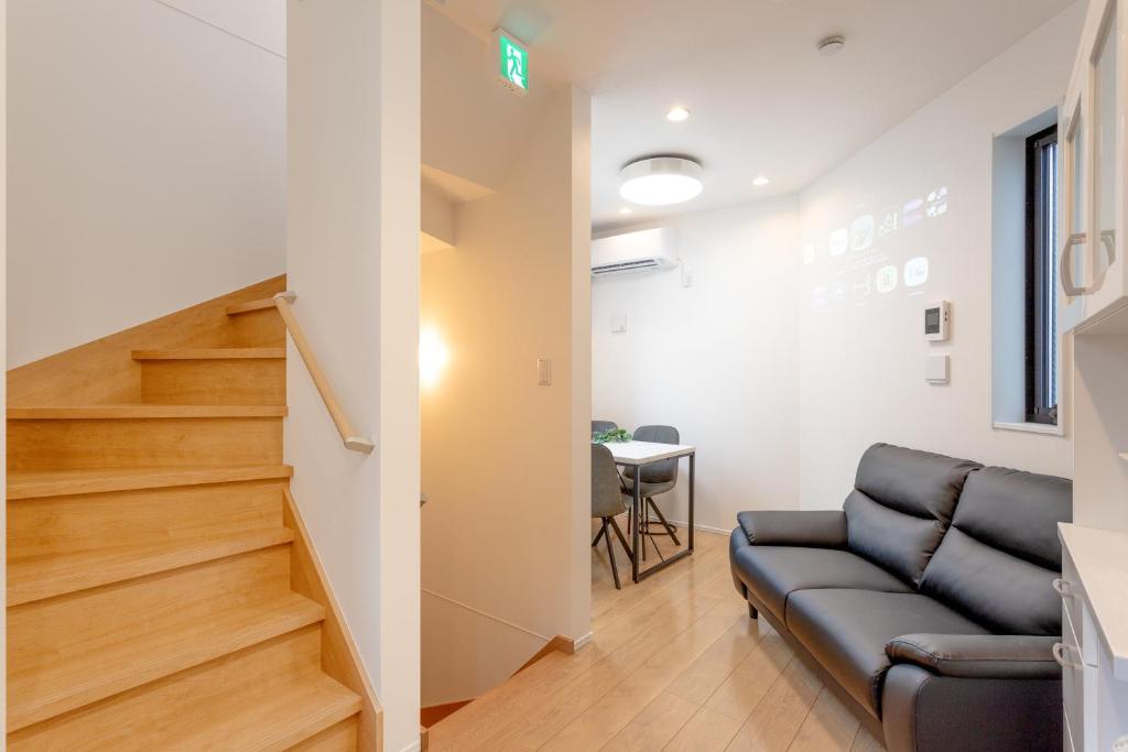 a living room with a couch and a staircase at Shinjuku City House 新宿シティハウス in Tokyo
