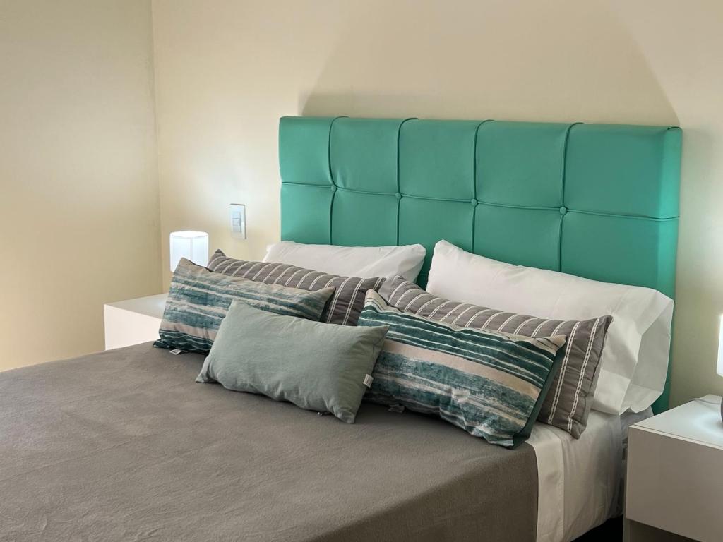 een bed met een blauw hoofdeinde en een aantal kussens bij Quinta Colores •con cochera• in Mendoza