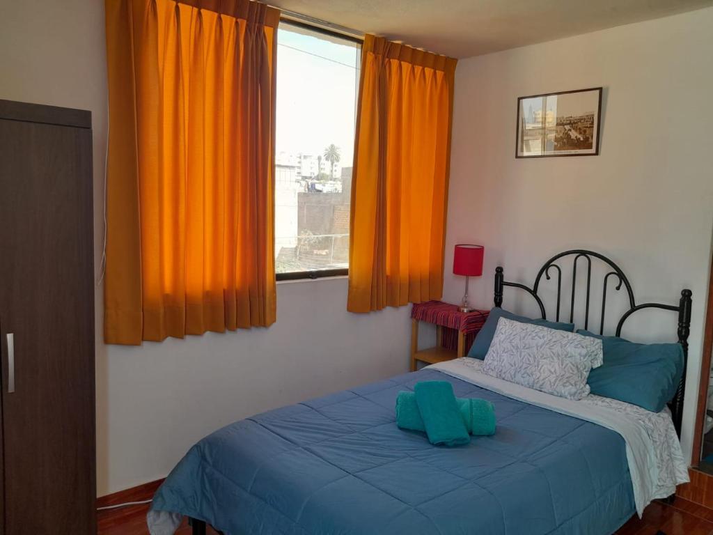 1 dormitorio con 1 cama y una ventana con cortinas de color naranja en AKAO HOUSE, en Arequipa
