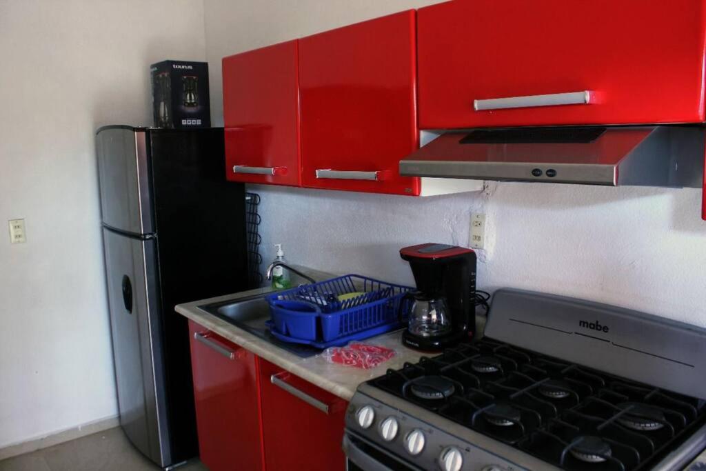 uma cozinha vermelha com um fogão e um frigorífico em departamento Sofía em Jaluco