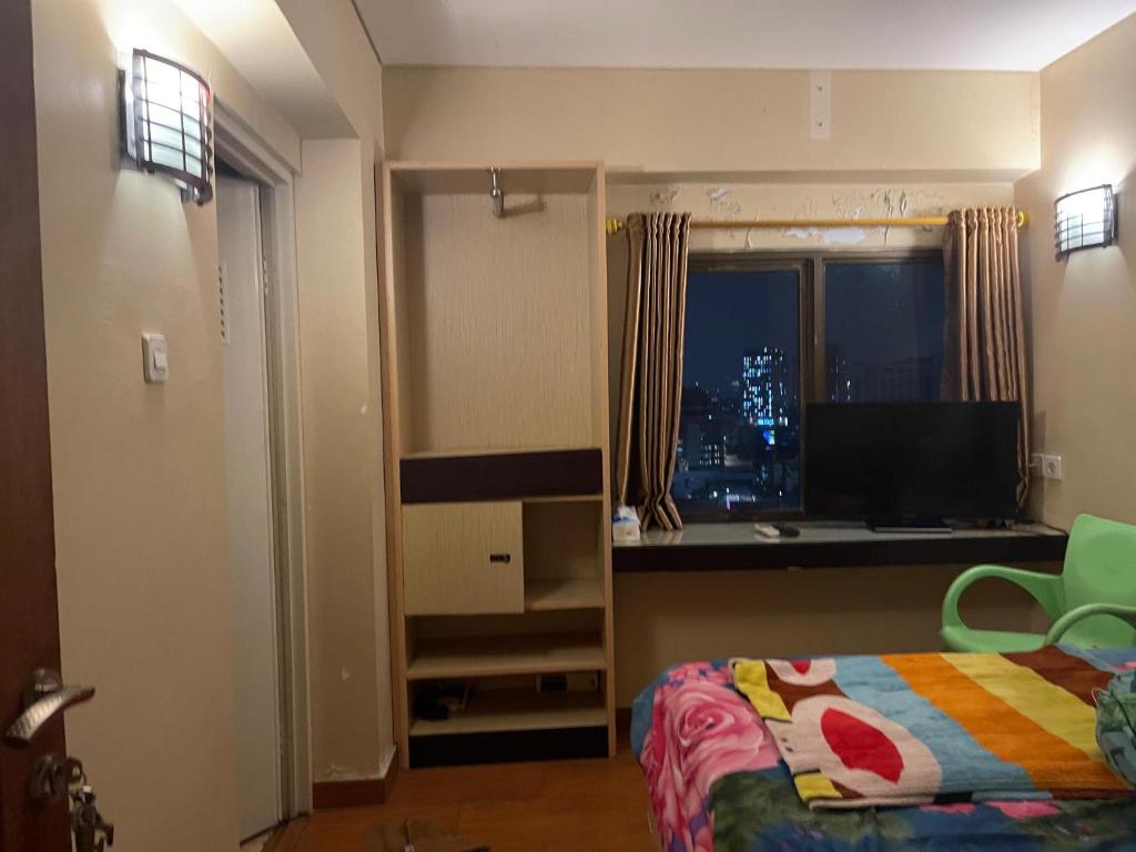 a bedroom with a bed and a tv and a window at Highlander Apartemen Rajawali in Jakarta