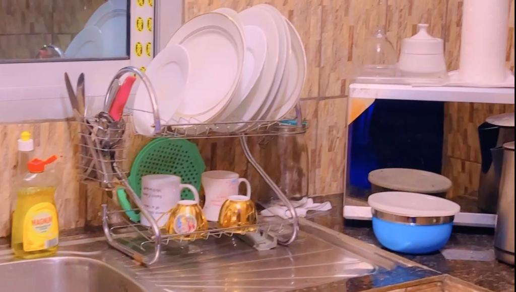 a kitchen sink with dishes in a dish rack at The Massango Guesthouse Limbe-Victoria Cameroon in Limbe