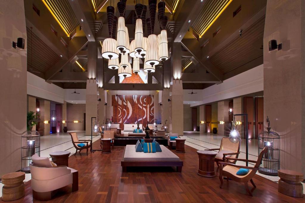 a lobby with a large chandelier and tables and chairs at Sheraton Grand Xishuangbanna Hotel in Jinghong