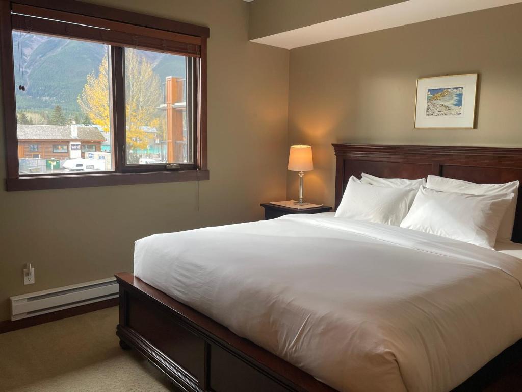 een slaapkamer met een groot wit bed en een raam bij Best Views of Canmore - 2Bed 2Bath in Canmore