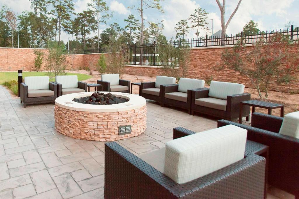 eine Terrasse mit mehreren Stühlen und einer Feuerstelle in der Unterkunft Courtyard by Marriott Houston City Place in Spring