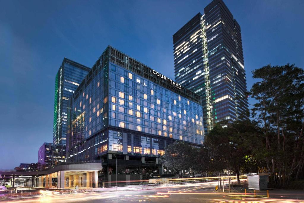 um edifício alto com luzes acesas numa cidade em Courtyard by Marriott Shenzhen Bay em Shenzhen