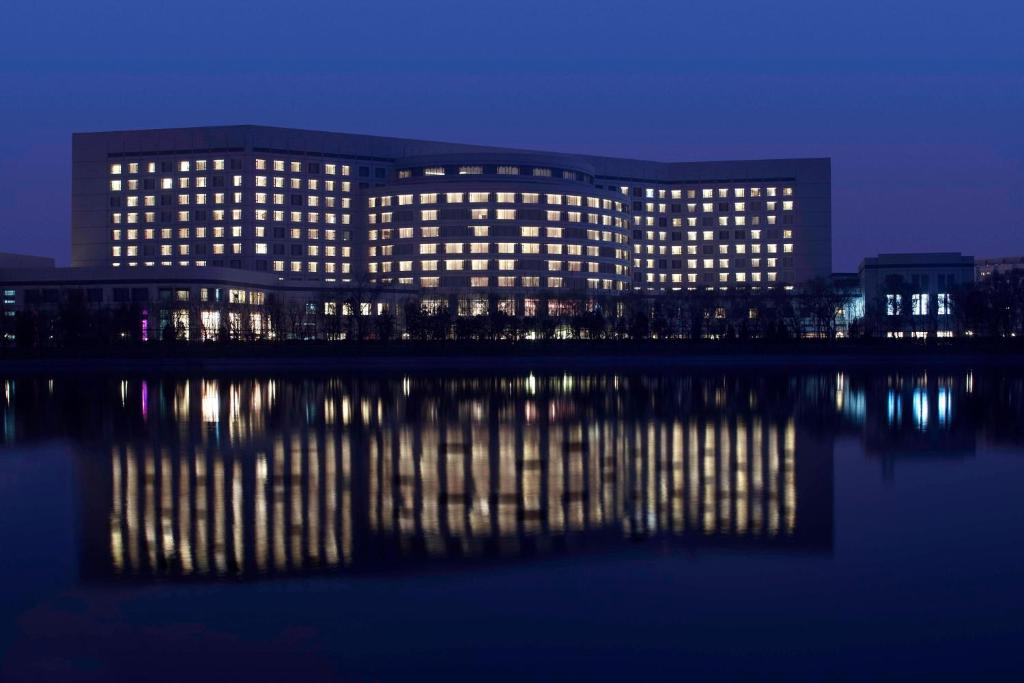 un gran edificio con luces en el agua por la noche en Marriott Executive Apartment Tianjin Lakeview en Tianjin