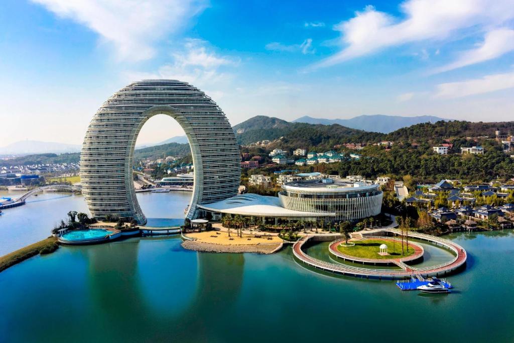 Sheraton Huzhou Taihu Lake Hot Spring Resort & Spa في هوتشو: اطلالة على مبنى به قوس في الماء