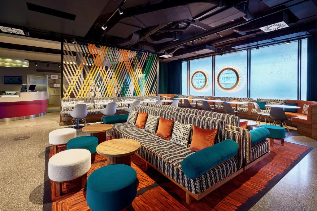 a waiting room with couches and tables and a stage at Aloft München in Munich