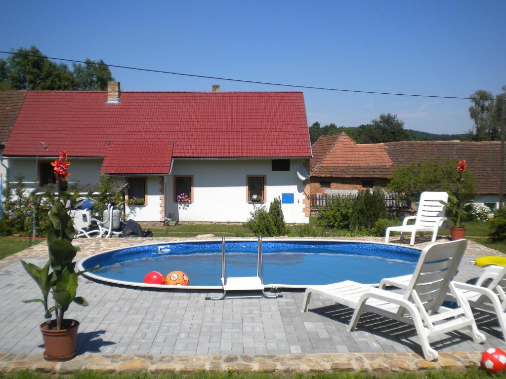 a swimming pool with two chairs and a house at Chalupa Tourov in Bavorov