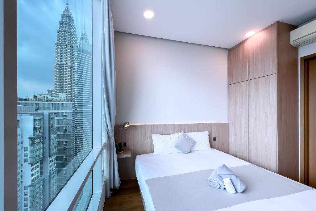 um quarto com uma cama branca e uma grande janela em Soho Suites KLCC by Leala em Kuala Lumpur