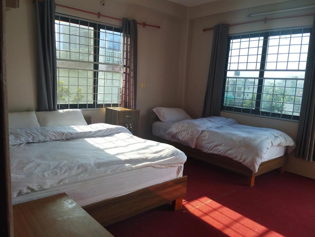 um quarto com 2 camas e 2 janelas em Namaste Stay Apartment em Pokhara