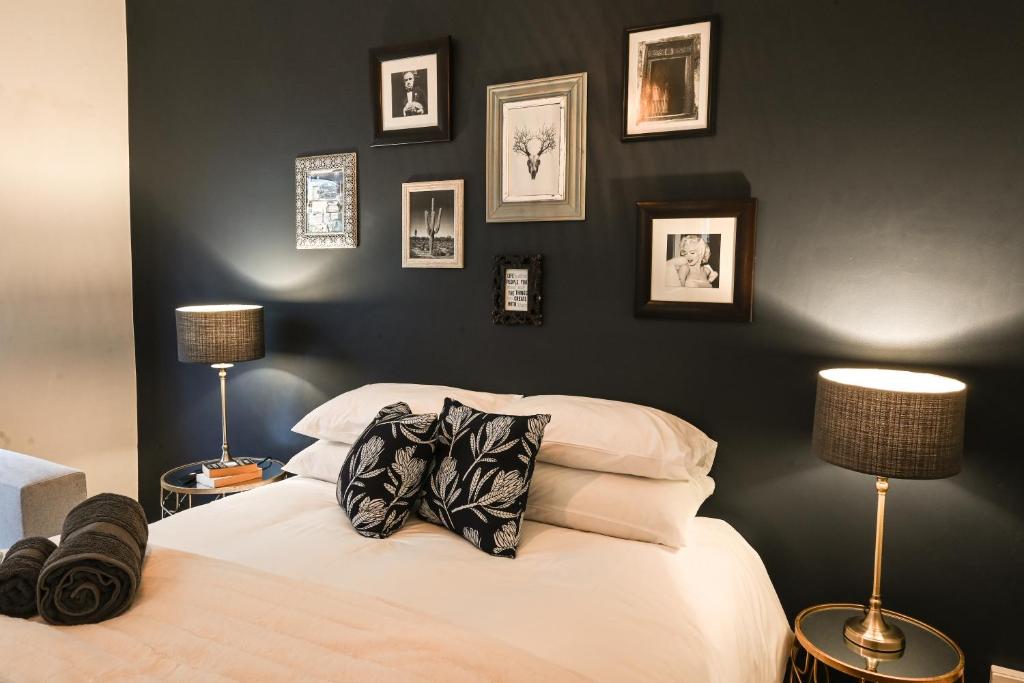 een slaapkamer met een bed met twee lampen en foto's aan de muur bij Eclectic Heritage Paradise Simon's Town in Simonʼs Town