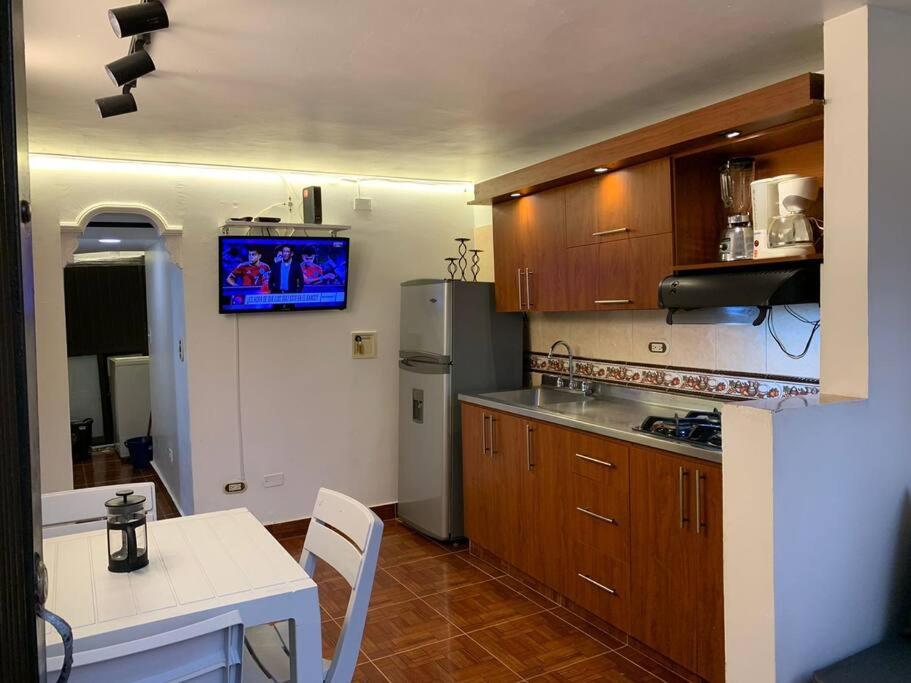 a kitchen with wooden cabinets and a table and a television at Acogedor Apartamento Urbanización Tricentenario in Medellín