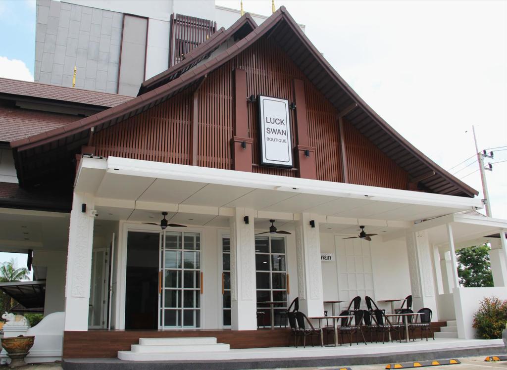 a building with tables and chairs in front of it at Luckswan Boutique Chiang Rai - SHA Extra Plus in Chiang Rai
