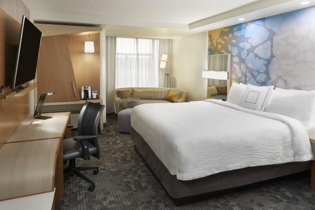 a hotel room with a large bed and a desk at Courtyard by Marriott Oshawa in Oshawa