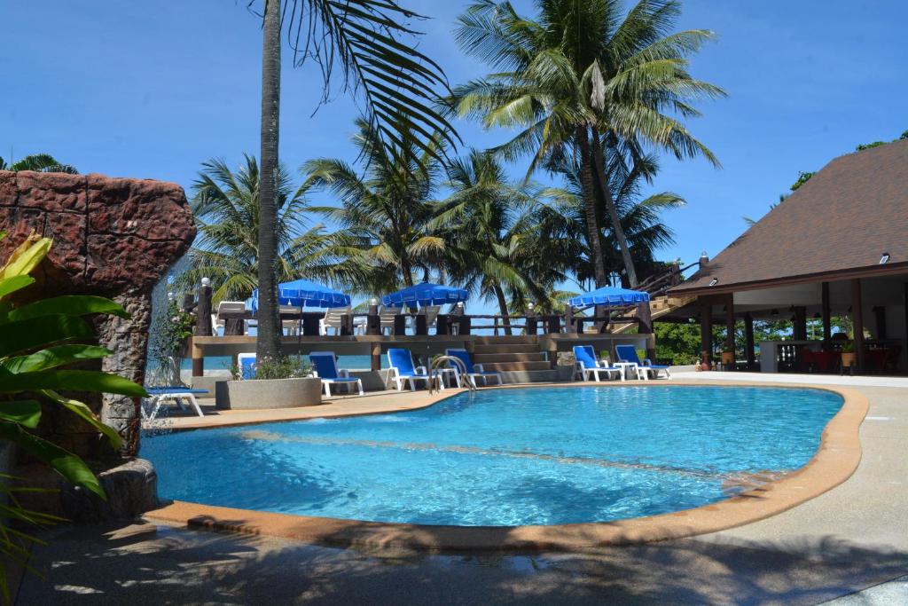 a pool at a resort with blue chairs and palm trees at Lanta IL Mare Beach Resort in Ko Lanta
