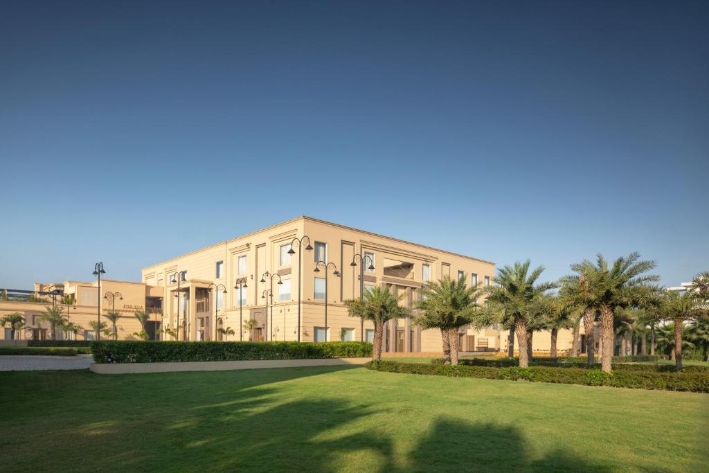 a large building with palm trees in front of it at Palasa Hotel in Muzaffarnagar