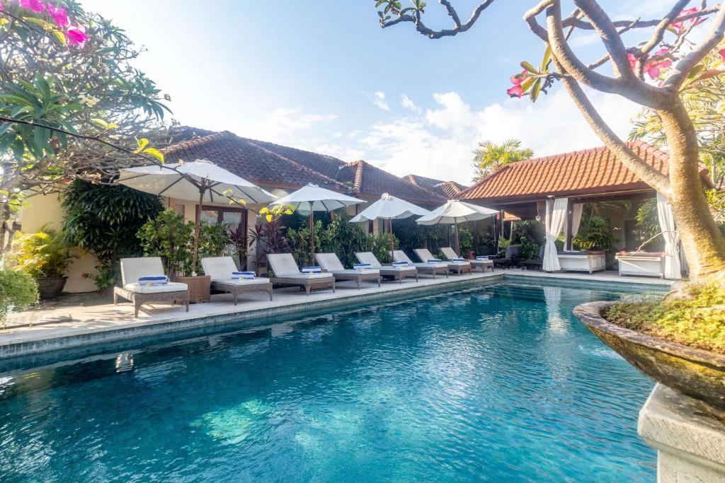 a pool at a resort with lounge chairs and umbrellas at Aleesha Villas and Suites in Sanur