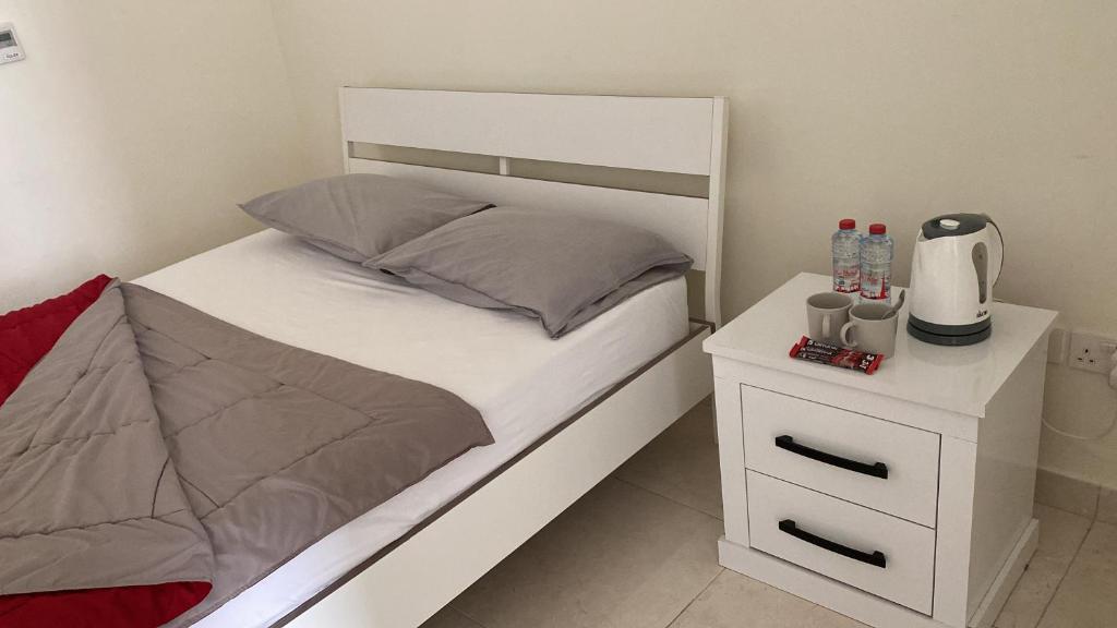 a bedroom with a white bed and a white night stand at Your apartment near Airport in Abu Dhabi
