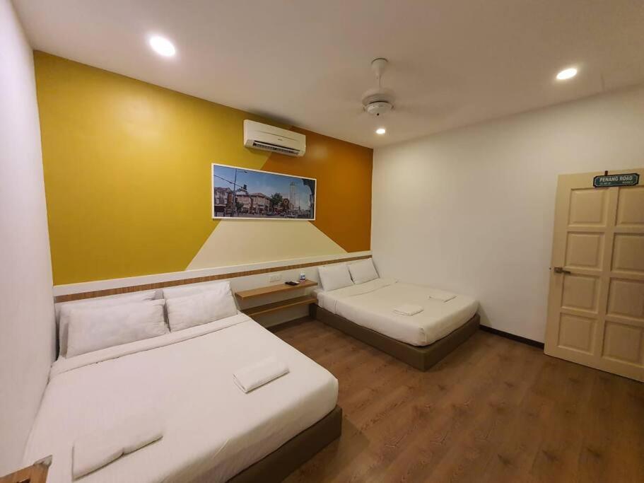 Cette chambre comprend 2 lits et un mur jaune. dans l'établissement PG56 Gurney Gleneagles Landed, à George Town