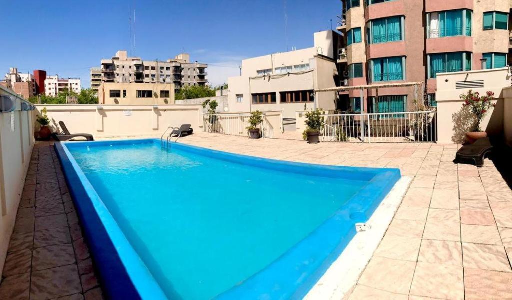 Lujoso departamento en la mejor ubicación de la ciudad de Mendoza con vista a la montaña في ميندوزا: مسبح ازرق فوق مبنى