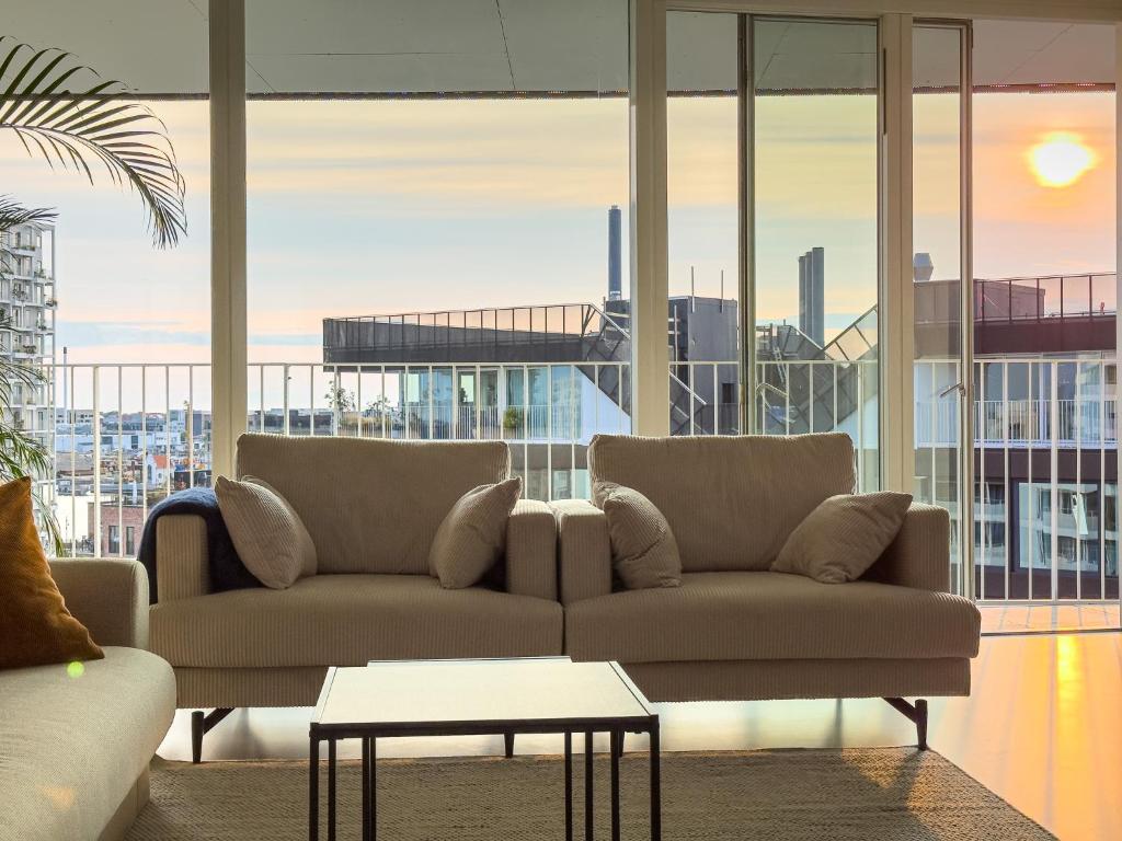 a living room with two couches and a table at Exclusive Penthouse with Sunset Views in Copenhagen