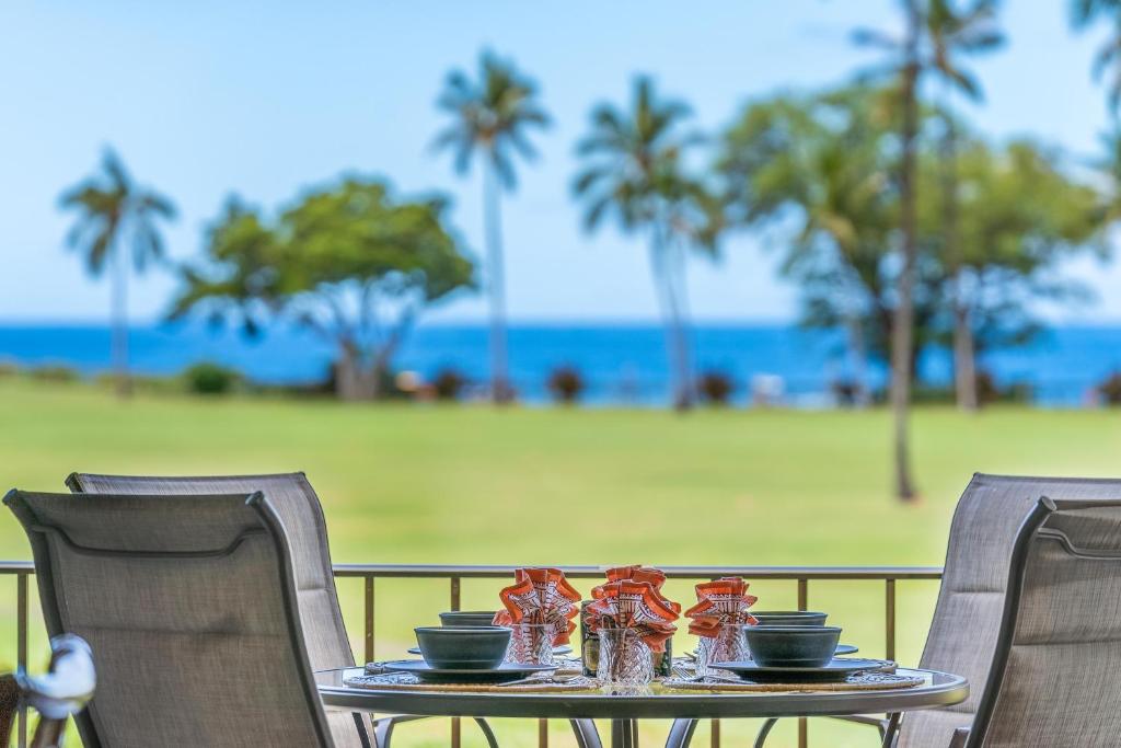 a table with bowls and plates on it with the beach at Eldorado J222 in Kahana