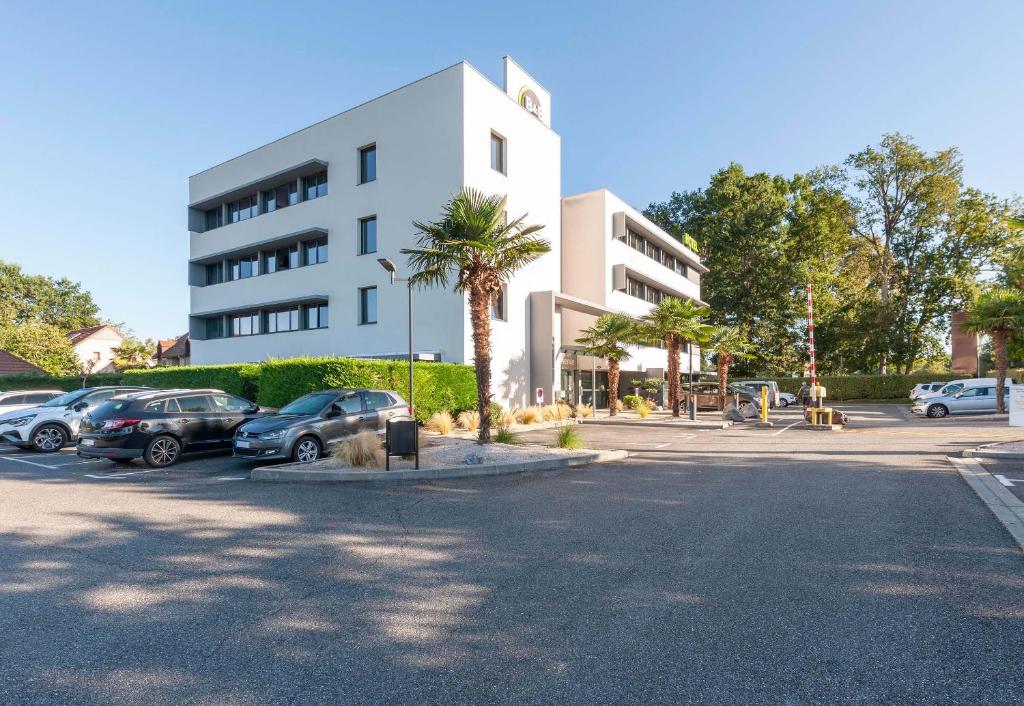 ein Parkplatz mit Autos vor einem Gebäude in der Unterkunft B&B HOTEL Pau Zénith in Pau