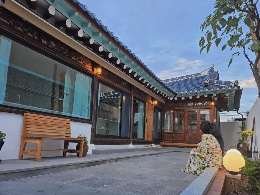 a woman in a dress sitting outside of a house at Exclusive House Hanok Stay 'Soo Hanok' in Suncheon