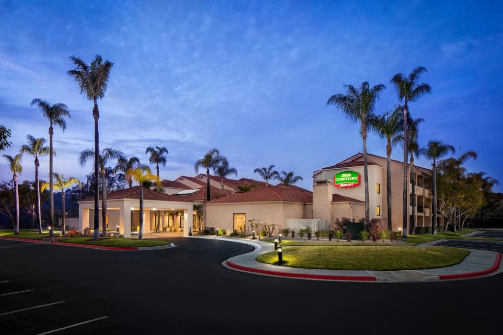 a hotel with palm trees in front of a building at Courtyard by Marriott San Diego Sorrento Valley in Sorrento