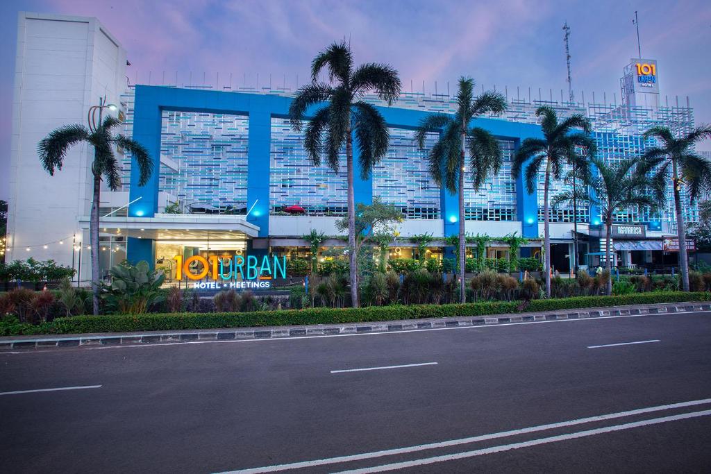 a building with palm trees in front of a street at 1O1 URBAN Jakarta Kelapa Gading in Jakarta