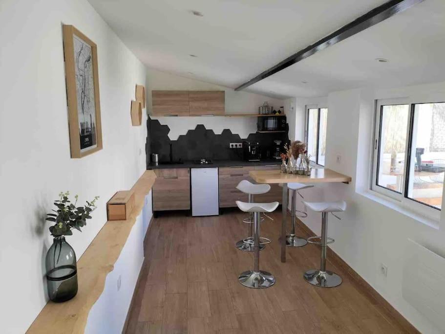 uma cozinha com um balcão e bancos num quarto em Micro maison Lyon 8/ Parking / Terrain de pétanque em Bron