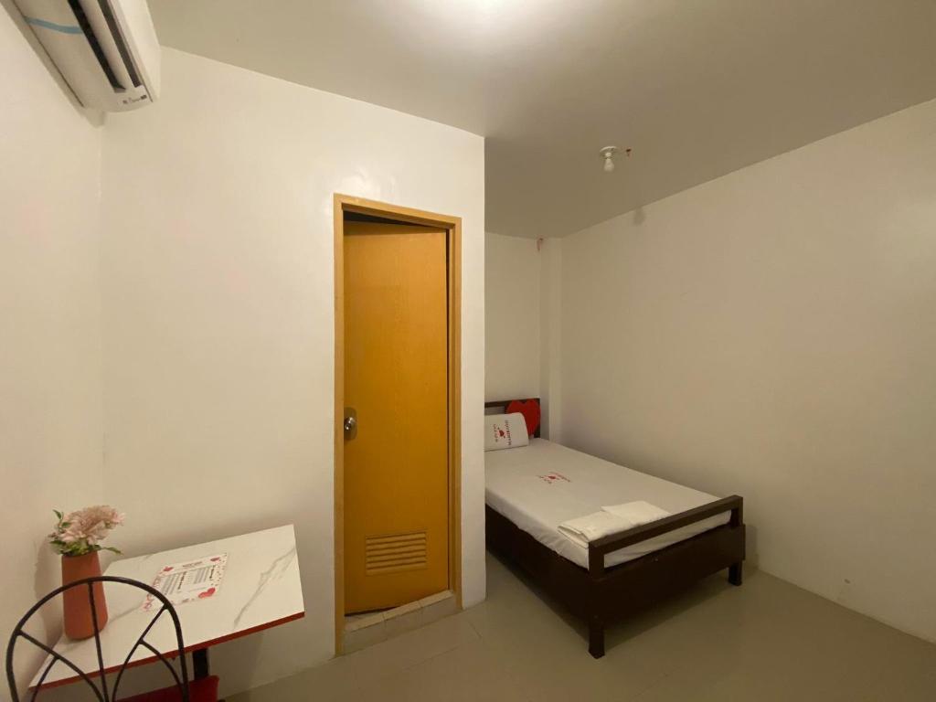 a small room with a small bed and a yellow door at WJV INN MARIBAG0 in Maribago
