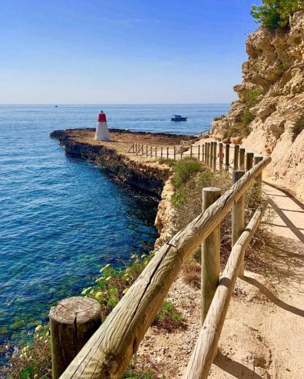 une clôture en bois à côté de l'océan avec un phare dans l'établissement Port de carry le rouet, à Carry-le-Rouet