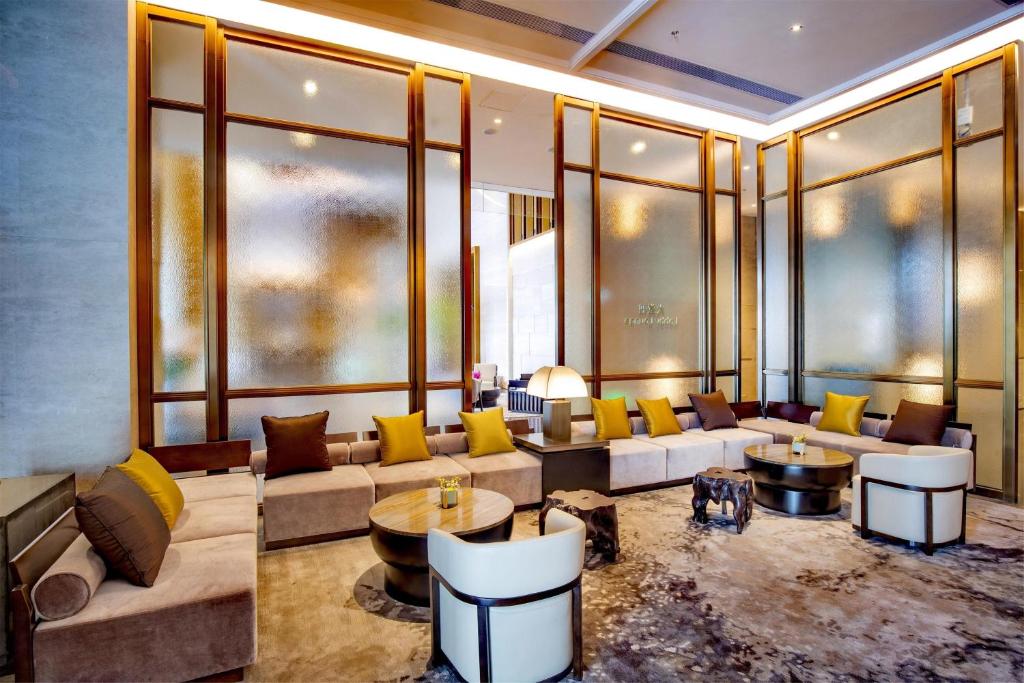 Sheraton Yunfu Xinxing Hotel في Yunfu: غرفة معيشة مع كنب وطاولات ونوافذ
